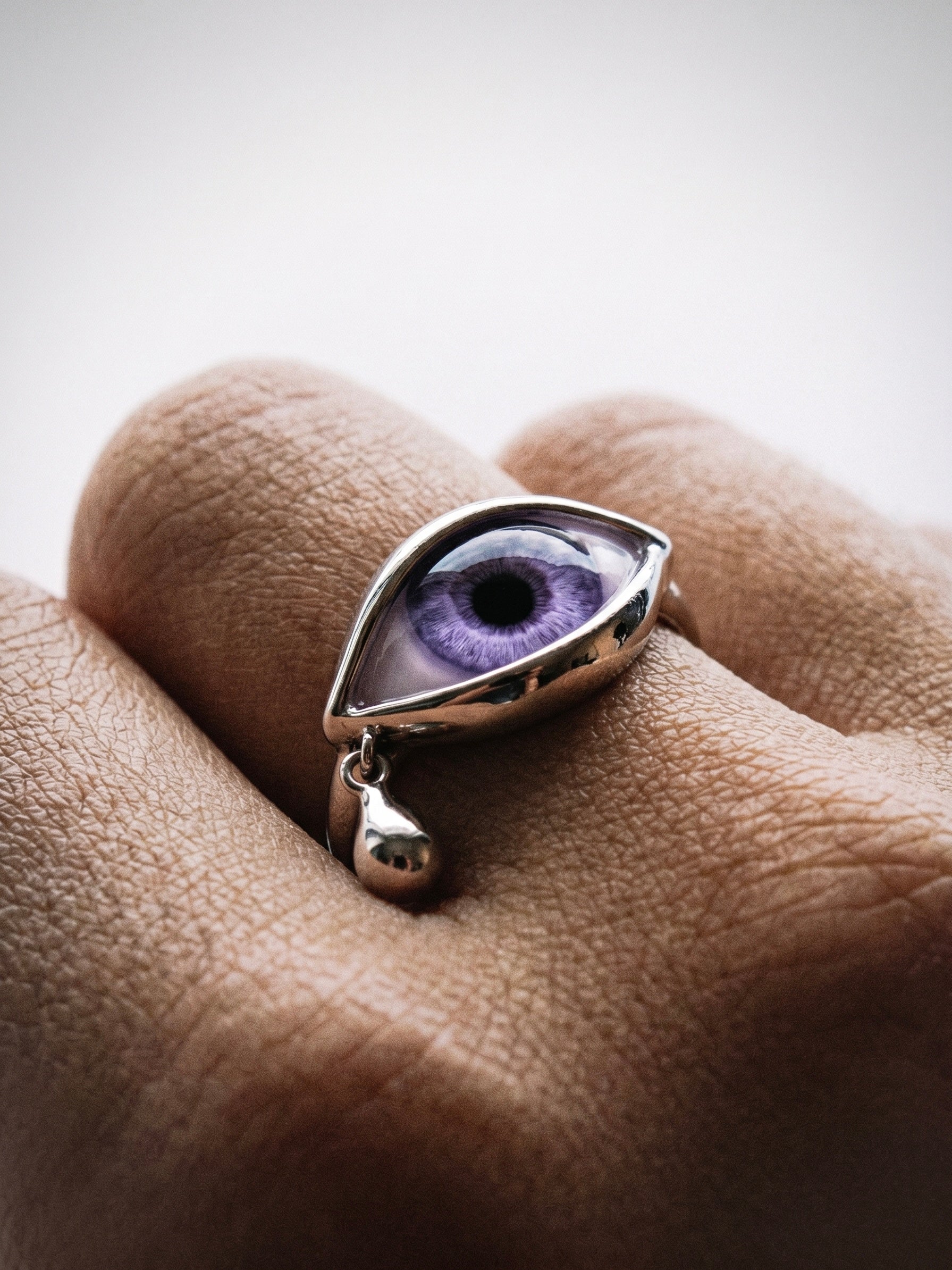 Pupil Bureau purple iris ring worn on hand